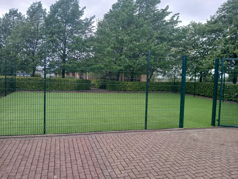 Artificial grass installation in a fenced school or nursery outdoor area.