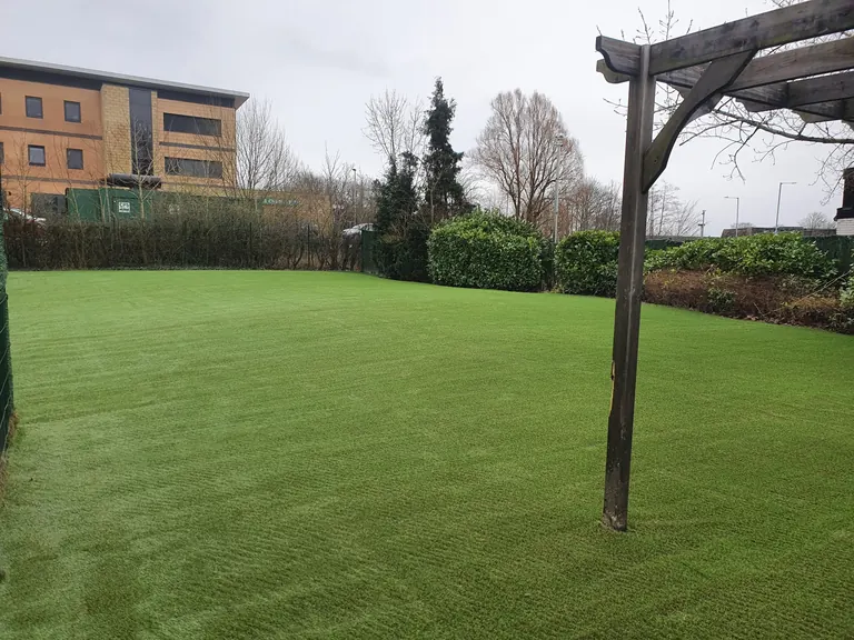 Large artificial grass outdoor area with an existing timber structure.