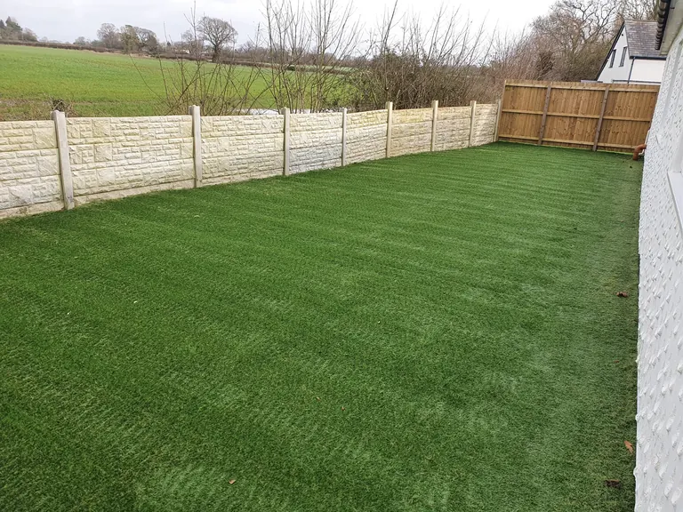 Completed artificial grass outdoor space beside the building.