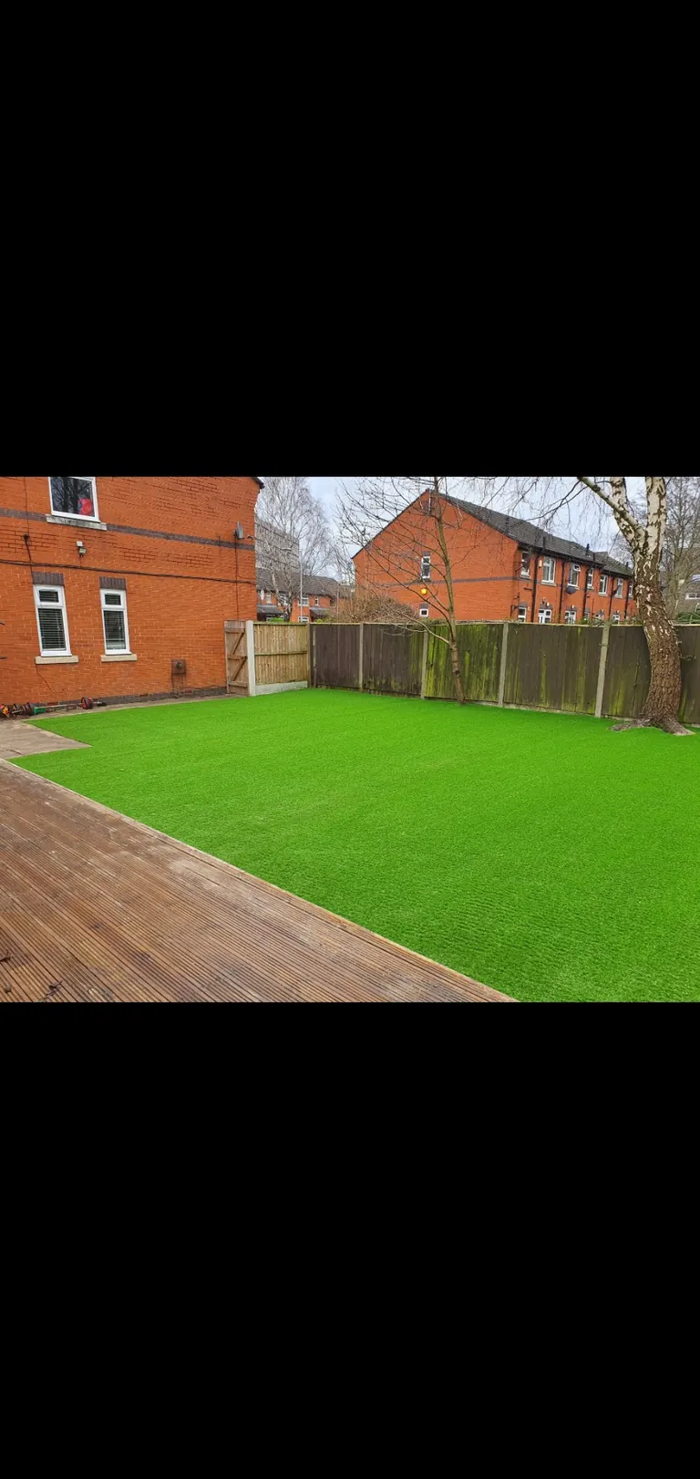 Artificial grass play space beside an existing decking area.